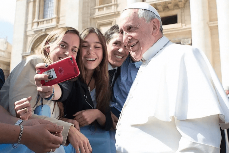 Pope Francis takes a selfie with pilgrims at the April 1, 2015 general audience in St. Peter’s Square. | Vatican Media. Pope Francis takes a selfie with pilgrims at the April 1, 2015 general audience in St. Peter’s Square. | Vatican Media.