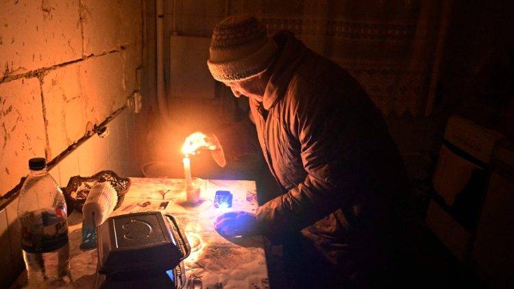 Ukraine elderly woman lights candle